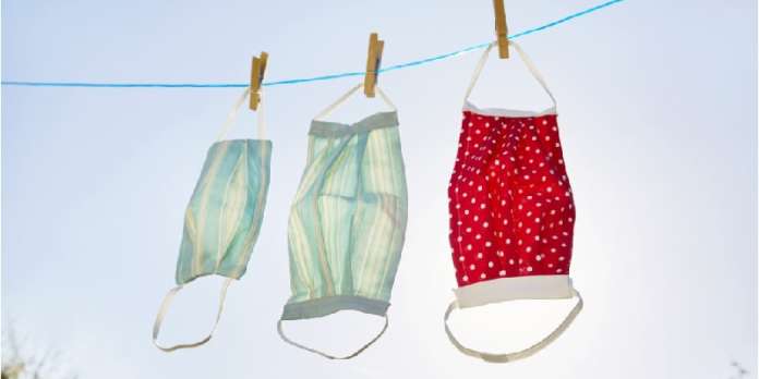 Still life of face masks hanging at clothesline against clear sky and sun, DIY sewing project