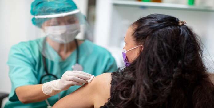 Female doctor in protective gloves cleansing patient's skin for vaccination